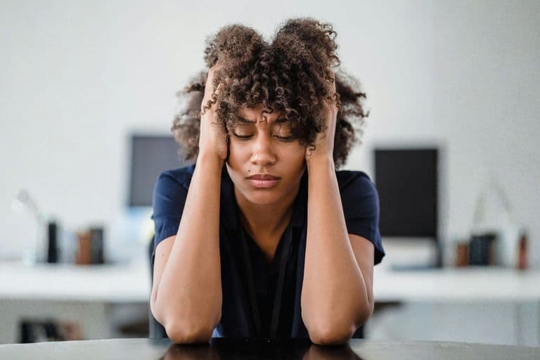 An image showing a person in deep concentration or feeling overwhelmed, with their hands on their head and eyes closed. 