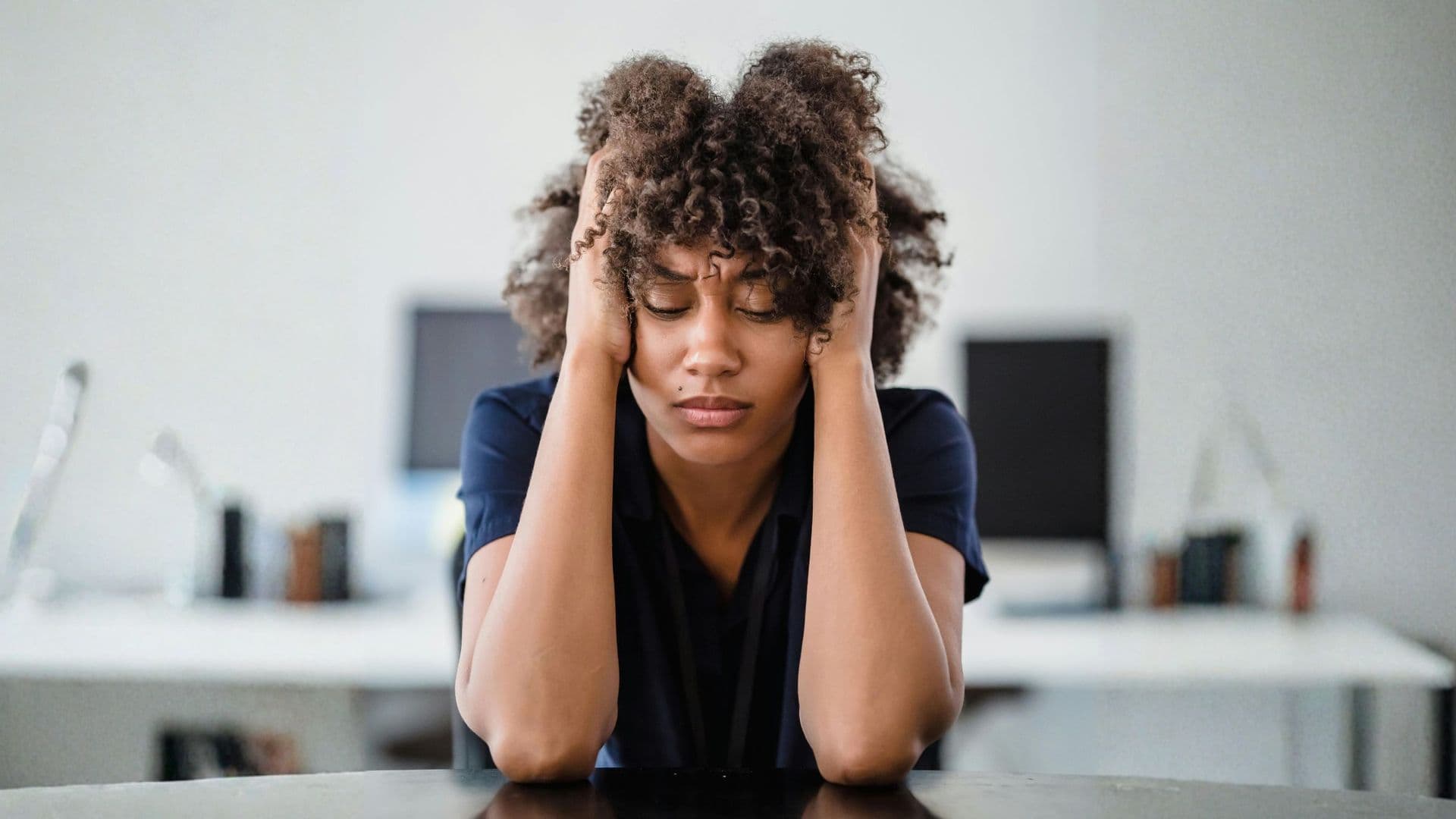 An image showing a person in deep concentration or feeling overwhelmed, with their hands on their head and eyes closed. 